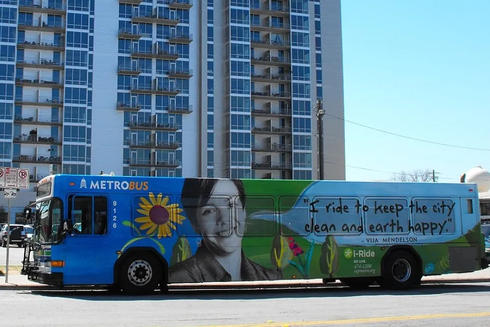 Blue Austin public transit bus with graphic reading "I ride to keep the city clean and earth happy."